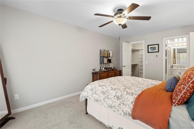 bedroom with ceiling fan, connected bathroom, light carpet, a spacious closet, and a closet