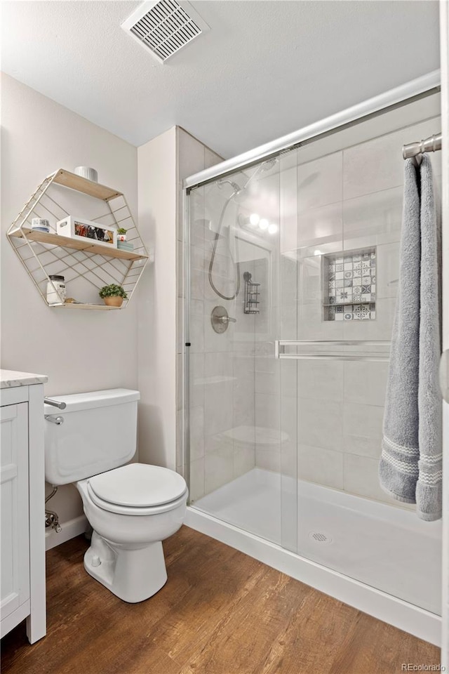 bathroom with walk in shower, vanity, toilet, and hardwood / wood-style floors