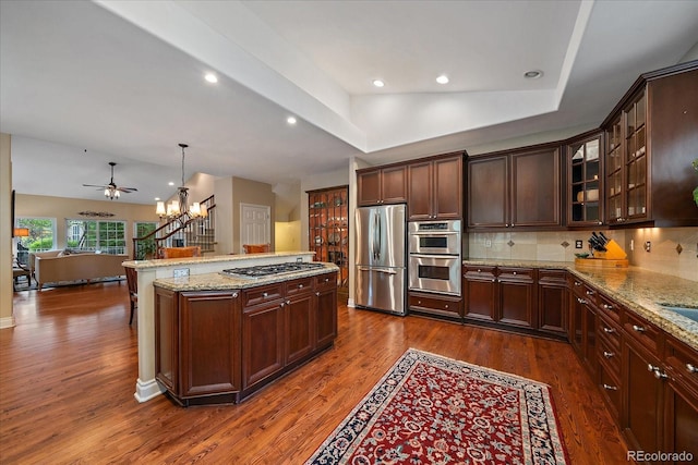 4545 S Monaco St Unit 243, Denver, CO 80237 - kitchen with appliances with stainless steel finishes, open floor plan, dark wood-style flooring, a chandelier, and tasteful backsplash