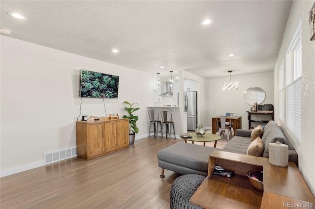2313 S Raleigh St, Denver, CO 80219 - living area with light wood finished floors, recessed lighting, a textured ceiling, and a chandelier