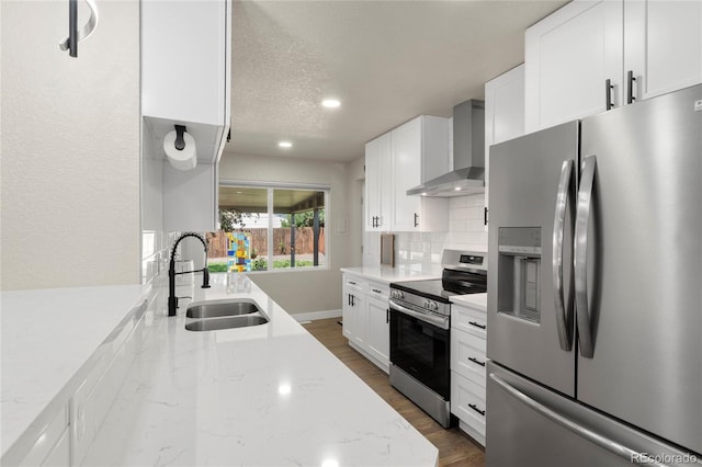 2313 S Raleigh St, Denver, CO 80219 - kitchen featuring appliances with stainless steel finishes, wall chimney exhaust hood, backsplash, dark wood-style floors, and white cabinetry