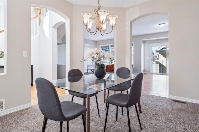 carpeted dining space featuring a healthy amount of sunlight and an inviting chandelier