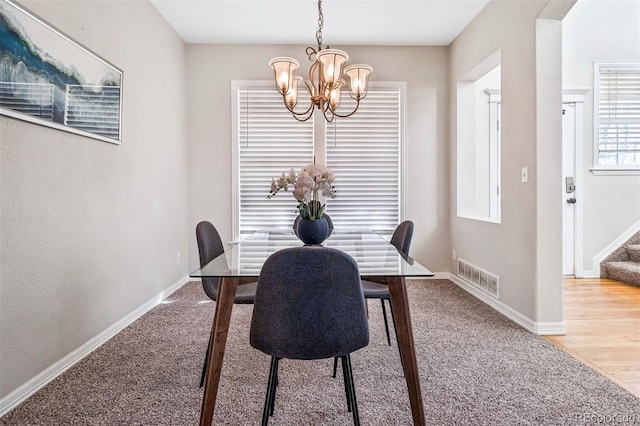 dining space with hardwood / wood-style floors and a chandelier