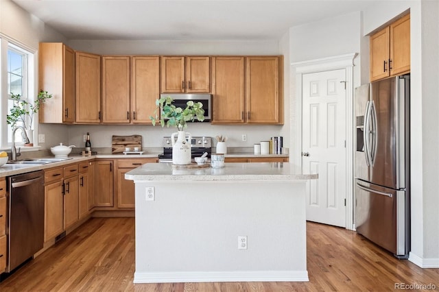 kitchen featuring sink, a center island, light hardwood / wood-style flooring, and appliances with stainless steel finishes