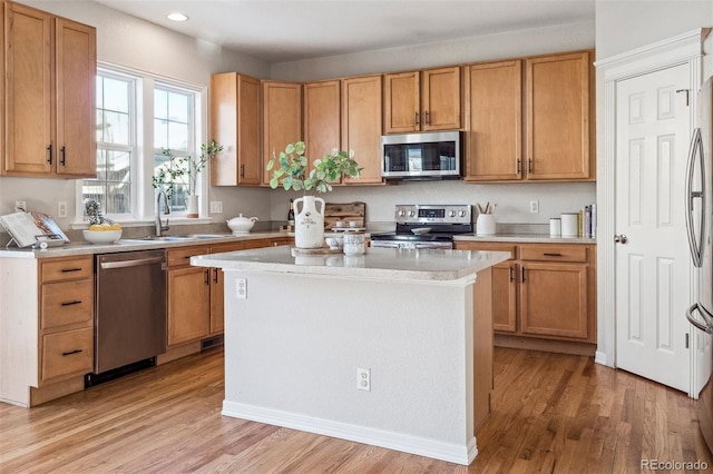 kitchen with a kitchen island, sink, appliances with stainless steel finishes, and light hardwood / wood-style flooring