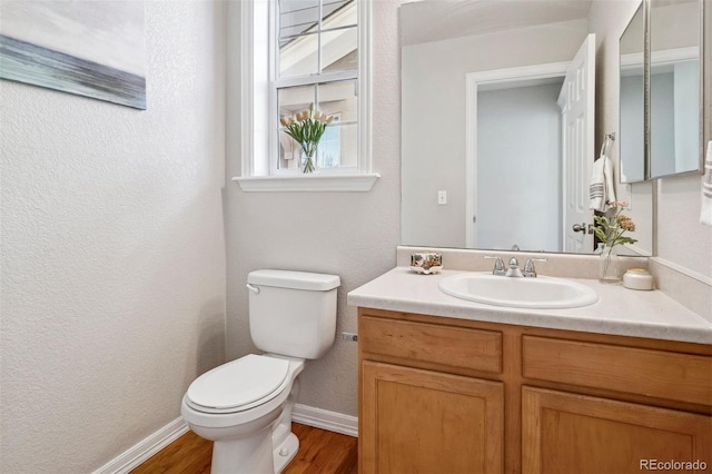 bathroom with hardwood / wood-style floors, vanity, and toilet