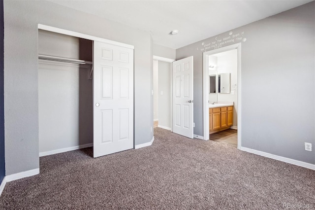 unfurnished bedroom with dark colored carpet, connected bathroom, and a closet