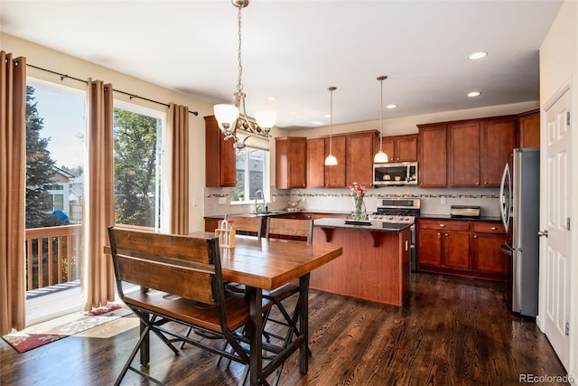 11460 W Tanforan Cir, Littleton, CO 80127 - kitchen featuring stainless steel appliances, dark countertops, dark wood-type flooring, backsplash, and a center island