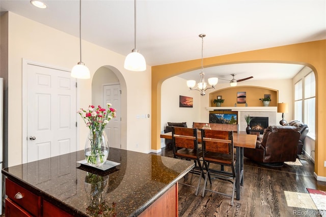 11460 W Tanforan Cir, Littleton, CO 80127 - kitchen featuring dark wood-type flooring, arched walkways, open floor plan, a chandelier, and a lit fireplace