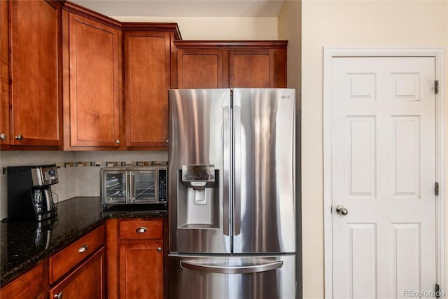 11460 W Tanforan Cir, Littleton, CO 80127 - kitchen featuring stainless steel fridge with ice dispenser, tasteful backsplash, dark stone counters, and brown cabinetry