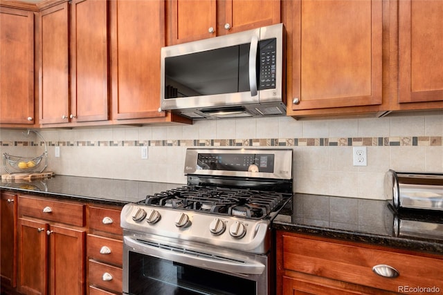 11460 W Tanforan Cir, Littleton, CO 80127 - kitchen featuring appliances with stainless steel finishes, backsplash, dark stone countertops, and brown cabinetry