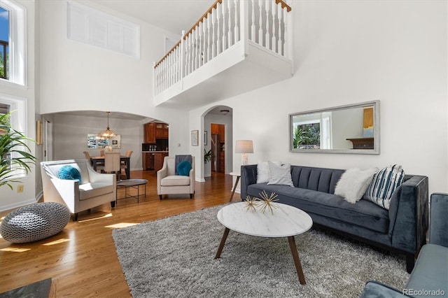 5922 E Briarwood Dr, Centennial, CO 80112 - living area featuring arched walkways, a towering ceiling, healthy amount of natural light, and wood finished floors