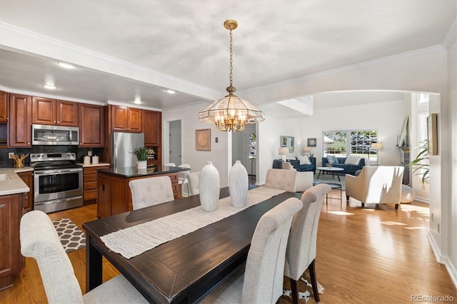 5922 E Briarwood Dr, Centennial, CO 80112 - dining room featuring a chandelier, light wood-style floors, crown molding, arched walkways, and recessed lighting