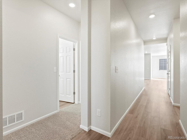 hallway with light wood-style flooring, recessed lighting, baseboards, and visible vents