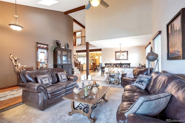 living room with beam ceiling, ceiling fan with notable chandelier, and high vaulted ceiling