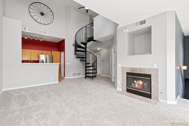 8707 E Florida Ave Unit 614, Denver, CO 80247 - unfurnished living room featuring carpet floors, a fireplace, stairway, track lighting, and baseboards