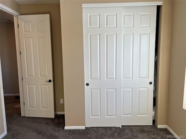 unfurnished bedroom with dark carpet and a closet