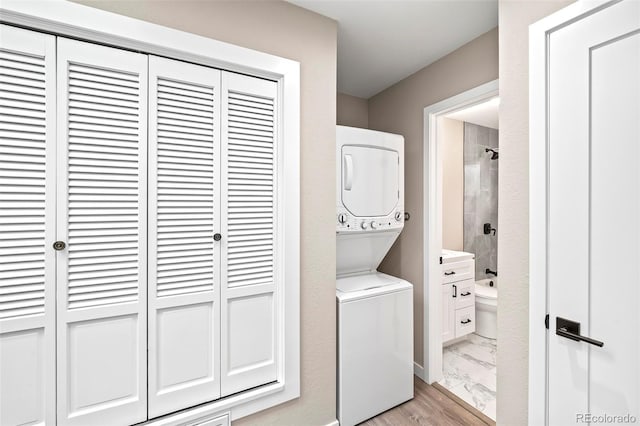 washroom featuring light hardwood / wood-style flooring and stacked washing maching and dryer