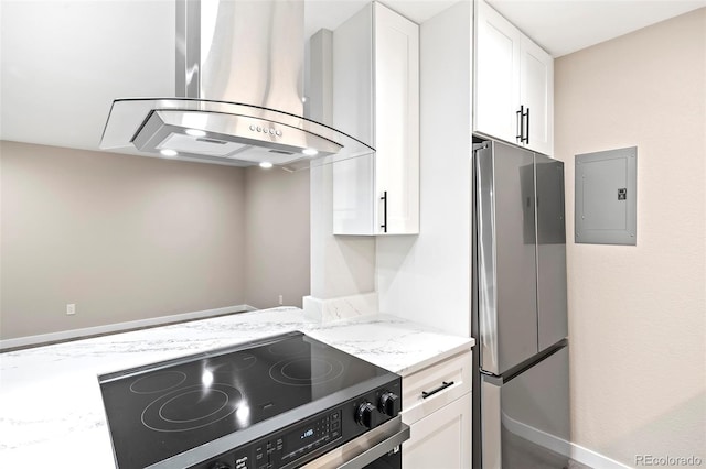 kitchen with light stone countertops, white cabinetry, stainless steel appliances, range hood, and electric panel