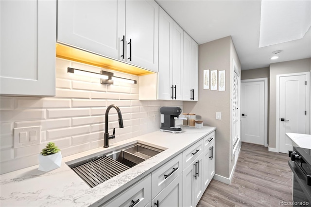 kitchen featuring tasteful backsplash, white cabinetry, and sink