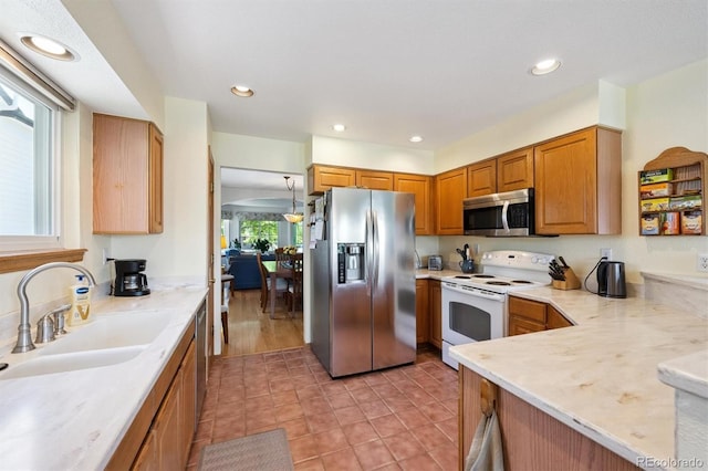 12963 W 84th Pl, Arvada, CO 80005 - kitchen with stainless steel appliances, recessed lighting, brown cabinets, and light tile patterned floors