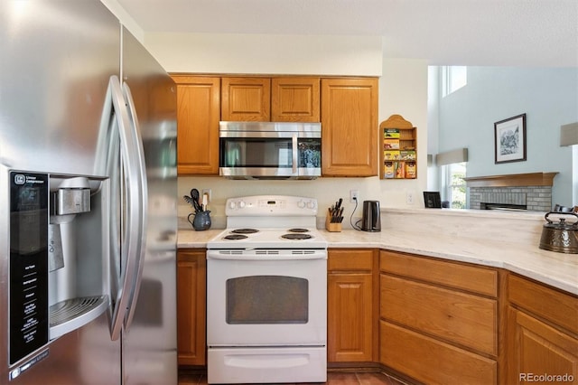 12963 W 84th Pl, Arvada, CO 80005 - kitchen featuring stainless steel appliances, brown cabinets, and a brick fireplace