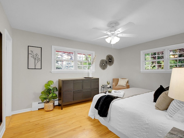 5895 W Plymouth Dr, Littleton, CO 80128 - bedroom with light wood-type flooring, multiple windows, a baseboard heating unit, and a ceiling fan