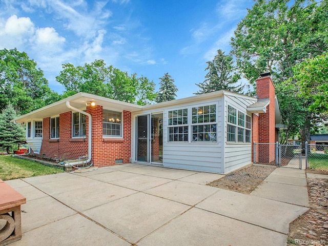 5895 W Plymouth Dr, Littleton, CO 80128 - view of front of property featuring brick siding, a chimney, a patio area, and a gate