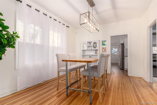 dining room with light hardwood / wood-style flooring, a healthy amount of sunlight, and an inviting chandelier