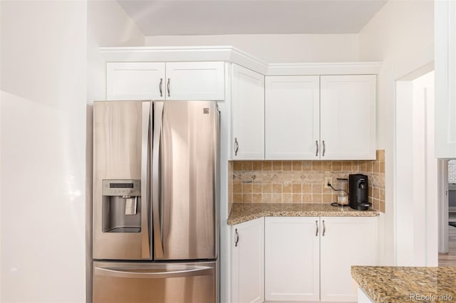 kitchen with white cabinets, light stone countertops, stainless steel refrigerator with ice dispenser, and tasteful backsplash