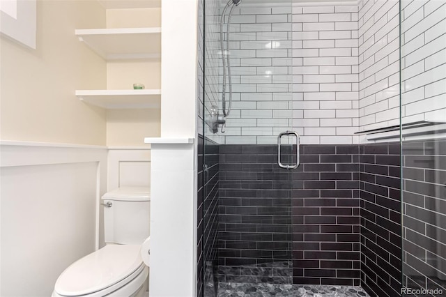 bathroom featuring toilet and a shower with shower door