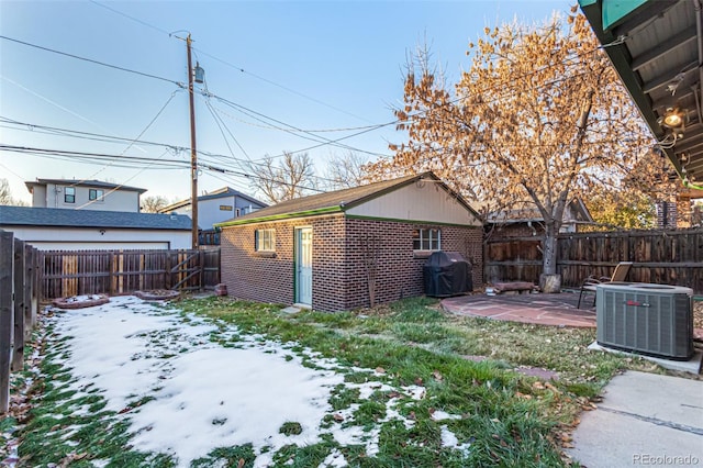 yard covered in snow with central air condition unit and a patio area