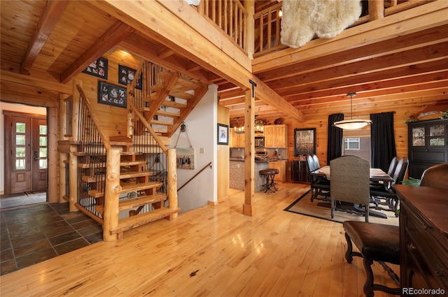 dining room with beam ceiling, wood walls, hardwood / wood-style flooring, and wood ceiling