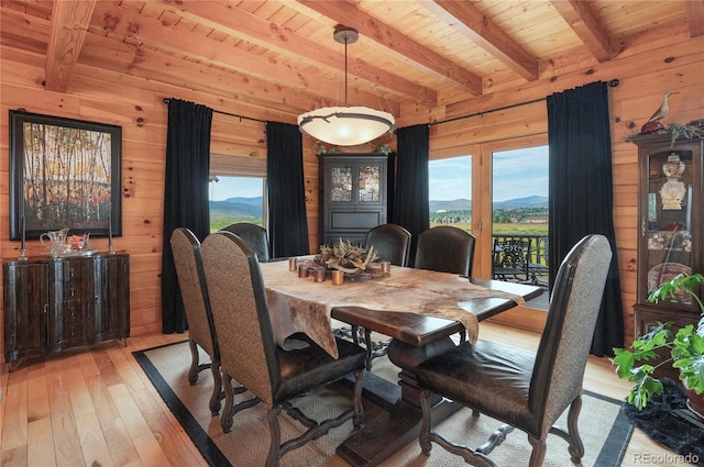 dining space featuring light wood-type flooring, wood walls, wood ceiling, and plenty of natural light