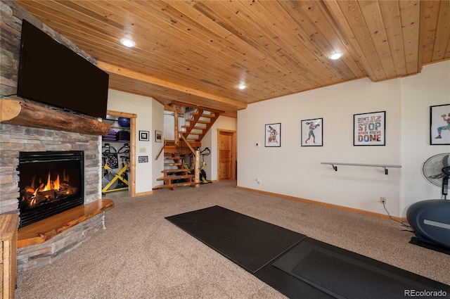 exercise room with wood ceiling, a stone fireplace, and carpet