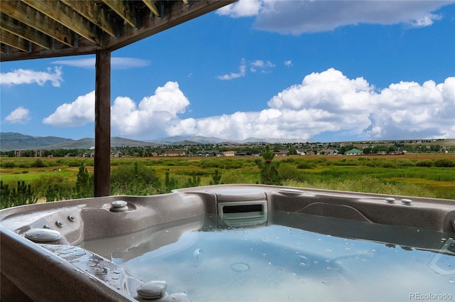 view of swimming pool featuring a hot tub, a mountain view, and a rural view