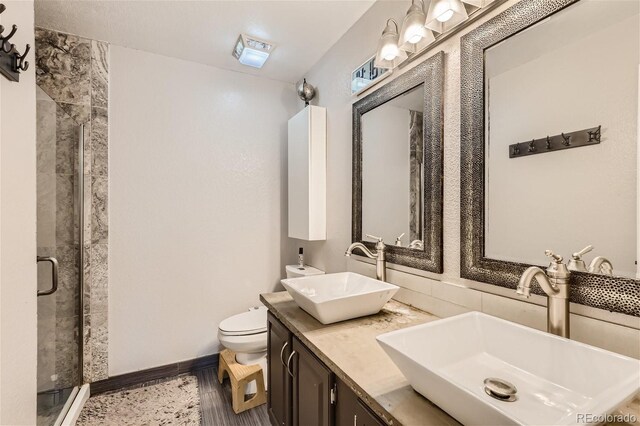 bathroom featuring dual vanity, a shower with door, and toilet