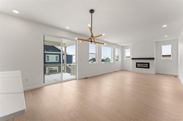 unfurnished living room featuring light wood-type flooring and an inviting chandelier