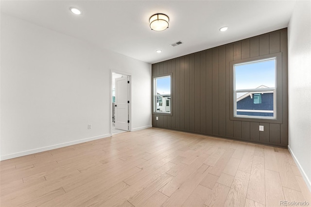 spare room featuring light wood-type flooring and wooden walls