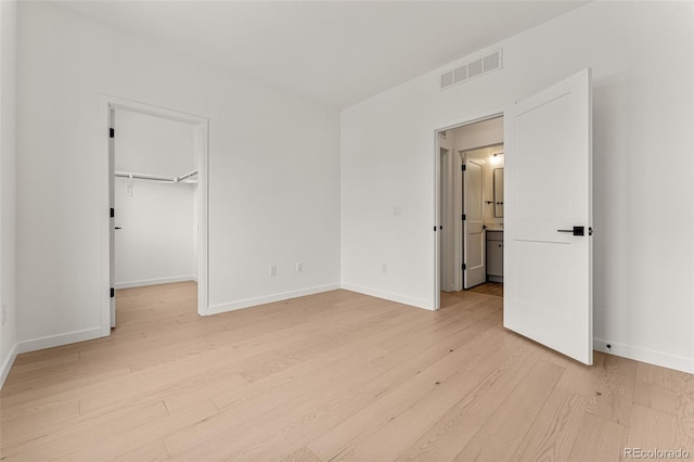 unfurnished bedroom with a closet, light hardwood / wood-style flooring, and a spacious closet