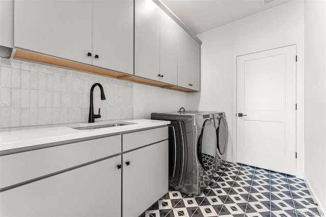 clothes washing area with dark tile patterned floors, cabinets, sink, and washing machine and clothes dryer