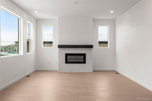 unfurnished living room with a tile fireplace and light wood-type flooring