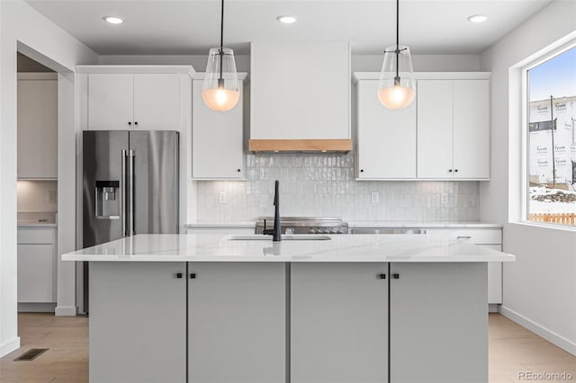 kitchen with white cabinetry, an island with sink, and light stone countertops