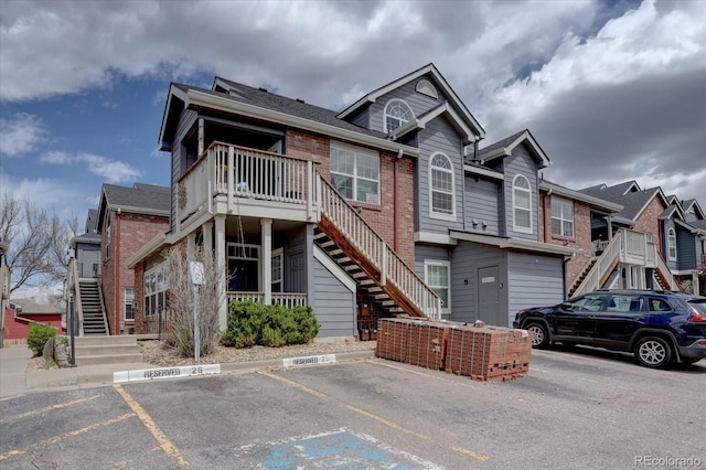 view of front facade with uncovered parking, brick siding, and stairs
