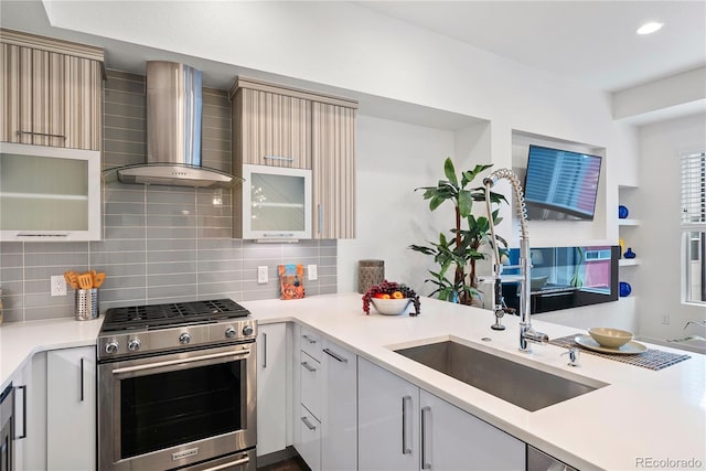 kitchen with backsplash, wall chimney exhaust hood, sink, and high end range