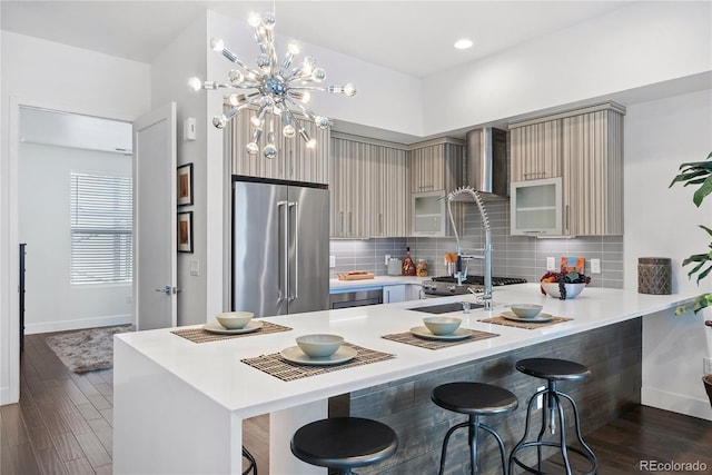 kitchen with kitchen peninsula, a kitchen breakfast bar, dark hardwood / wood-style flooring, tasteful backsplash, and high quality fridge