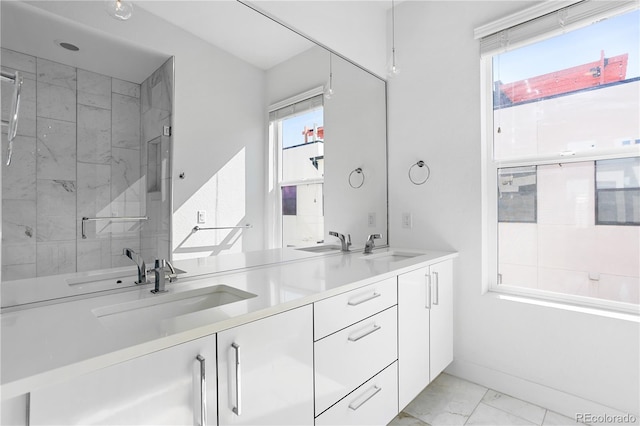 bathroom with vanity, a shower with shower door, and a wealth of natural light