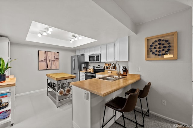 kitchen with a kitchen bar, white cabinets, kitchen peninsula, sink, and appliances with stainless steel finishes