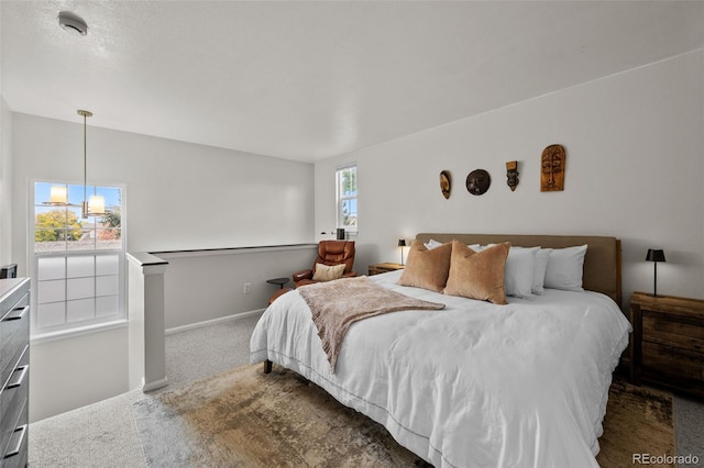 carpeted bedroom featuring multiple windows and a chandelier