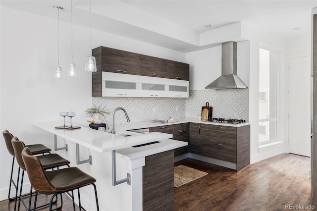 1715 Boulder St, Denver, CO 80211 - kitchen featuring wall chimney range hood, modern cabinets, light countertops, a breakfast bar area, and a peninsula